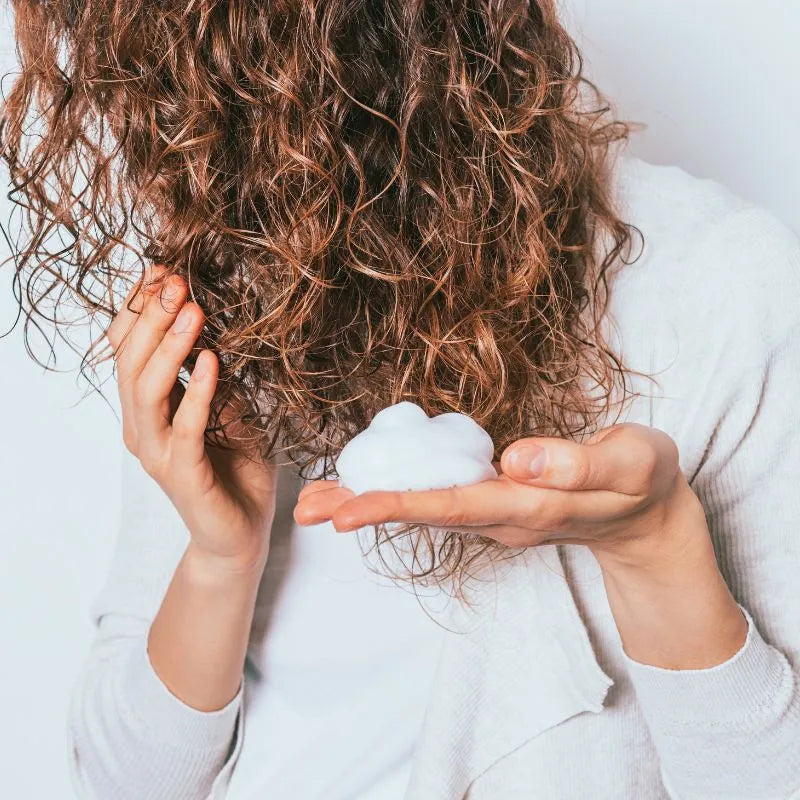 Femme qui se met de la mousse dans les cheveux